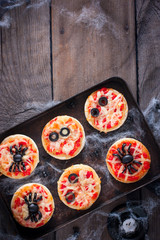 The idea of a festive meal for Halloween: mini pizza with spiders, mummy and spiderweb, copy space, top view