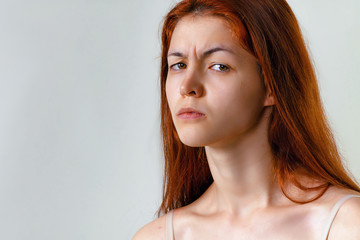 Feeling and emotions. Fashion portrait of nice redhead woman face expression, looking at camera and frown while posing on grey background copy space.