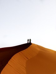 People standing atop sand dunes.