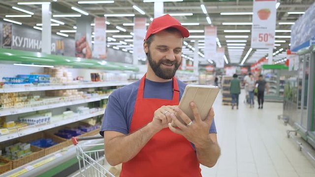 Happy salesperson using a digital tablet in supermarket