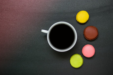 Top view cup of coffee and french macaron on black background, good morning