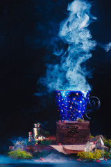 Ceramic cup with constellations and stars in a magical still life. Astronomer or astrologer workplace with smoke, crystals, moss and potion bottles. Magical concept with copy space