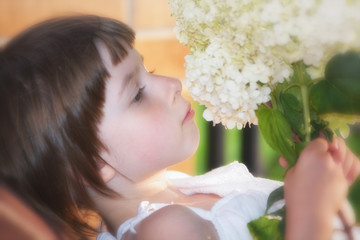 Obraz na płótnie Canvas Girl in an elegant white dress with garden flowers