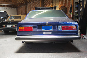 A rear view of a vintage classic car in a repair shop