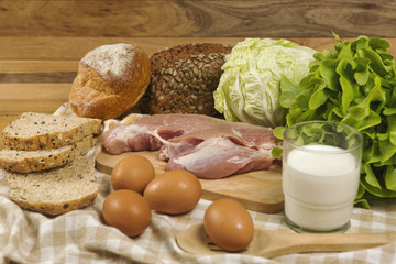 Set products consisting of bread, milk, pork, eggs , and vegetable on wooden table background, fresh food for cooking