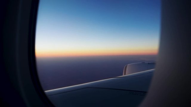 Looking out of plan window to sunset on horizon.