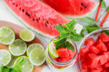 Slices of watermelon and lime placed in a jar to fill with water.