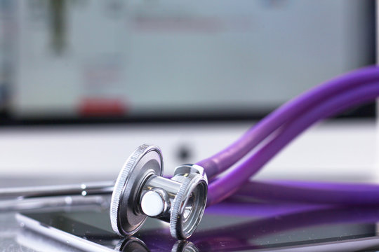 A medical stethoscope near a laptop on table, on white