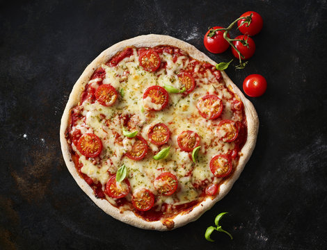 Pizza Margherita and cherry tomatoes on dark ground