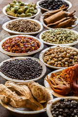 Group of Indian spices in coconut bowls on wooden background close-up.