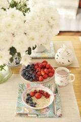 A large bouquet of white flowers on the table and breakfast for the family. Cozy house and delicious food. Seasonal Fruits, pastries and fragrant coffee. Copy space.