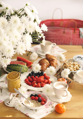 A large bouquet of white flowers on the table and breakfast for the family. Cozy house and tasty food. Fruit, pastries and fragrant coffee. Copy space,
