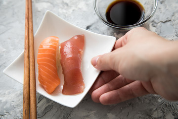 Frau serviert Lachs und Tunfisch Nigiri Sushi mit Sojasauce und Holz Stäbchen auf Porzellan Teller