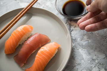 Frau serviert Lachs und Tunfisch Nigiri Sushi mit Sojasauce und Holz Stäbchen auf Porzellan Teller