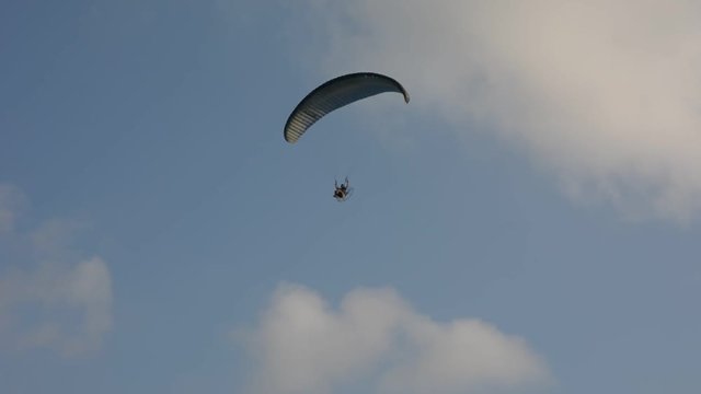 Silhouette of a male paraglider on a paraplan against a background of a sunset in the sky and clouds hovering over the sea. Concept: freedom, loneliness, hobby, sport.
