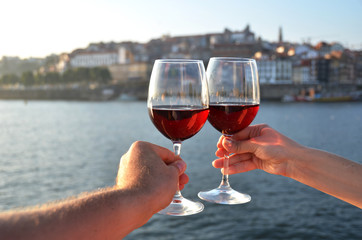 Wine glasses in the hands against Douro river in Porto, Portugal