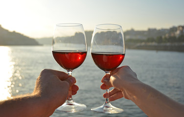 Wine glasses in the hands against Douro river in Porto, Portugal