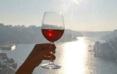 Wine glasses in the hands against Douro river in Porto, Portugal