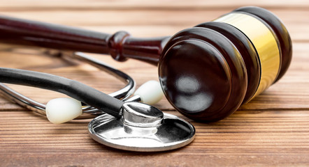 Gavel with stethoscope on wooden table. Medical law.