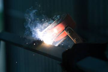 welder is welding metal part with lots of sparks