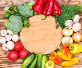 Cutting board with different vegetables on wooden background. Top view. Copy space.