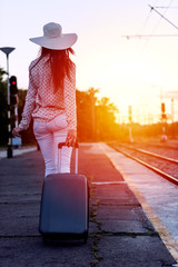 Young woman with luggage on train station waiting