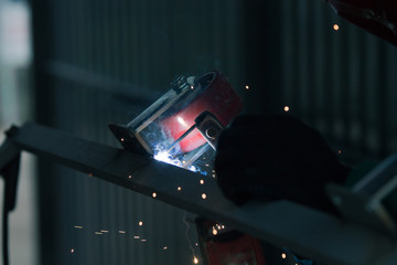 welder is welding metal part with lots of sparks