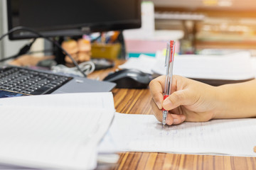 Teacher is checking on student's homework assignment documents which assigned to students to be completed outside the class. Stack of papers were not complete on table.