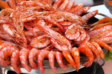 Grilled shrimps close up served on a plate on open kitchen food festival event . Street food  cooking concept.