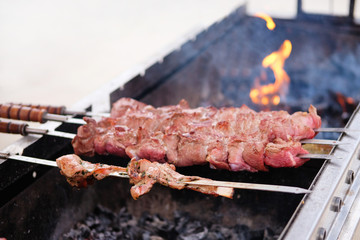 Meat frying on grill. Fried pieces of pork and beef skewers on coals in open air. Barbecue meat background.