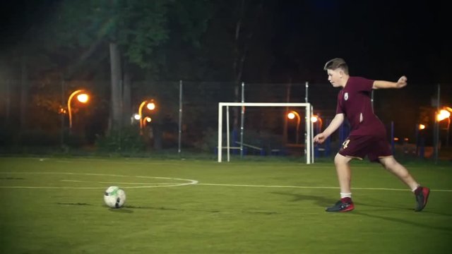 Young man runs up to the ball and kicks it, jumping on the spot