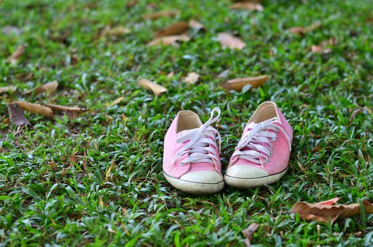 Pink sneakers on a green grass. Rest in the park without shoes.