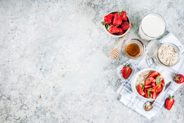 Healthy summer breakfast, overnight oatmeal with fresh strawberry and milk, grey stone background top view