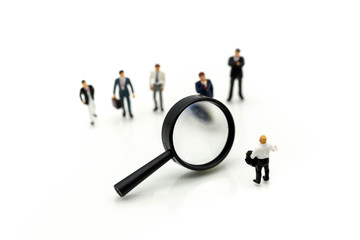 Miniature people: Magnifying glass focusing on the selected of businessman ,recruitment process, HR, HRM, HRD concepts.