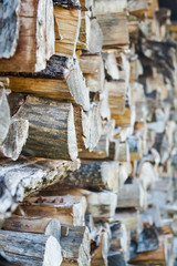 Fototapeta na wymiar Side view of stacked up, chopped firewood logs in a pile; selective focus