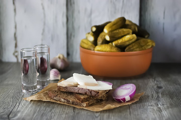 Marinated cucumbers, bacon, rye bread, onions and garlic and two glasses of vodka. Traditional Russian snack.