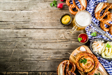 Oktoberfest food menu, bavarian sausages with pretzels, mashed potato, sauerkraut, beer bottle and mug old rustic wooden background, copy space above