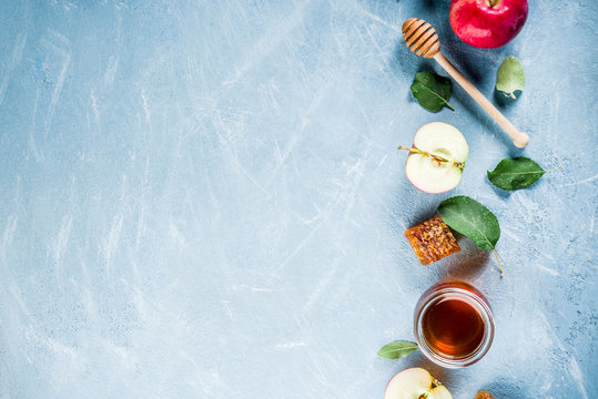 Jewish holiday Rosh Hashanah or apple feast day concept, with red apples, apple leaves and honey in jar, light blue background copy space above