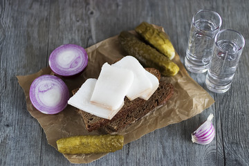 Marinated cucumbers, bacon, rye bread, onions and garlic and two glasses of vodka. Traditional Russian snack.