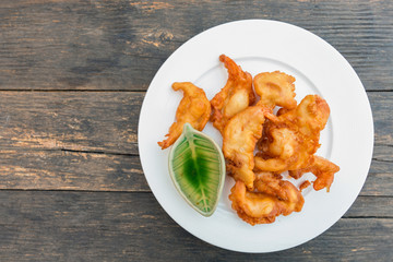 Top view of batter fried prawns in white dish on wooden table with a copy space