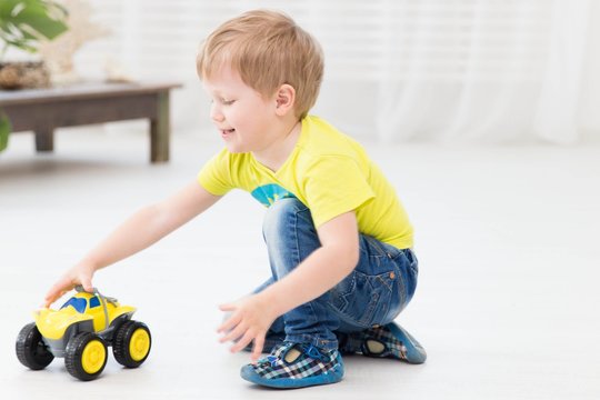 happy childhood - little cheerful little boy playing at home with toy car