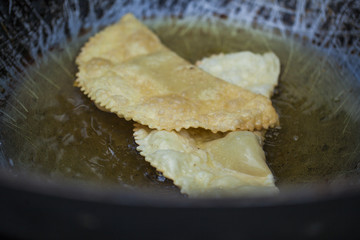 Uzbek cheburek fried in oil in a vat