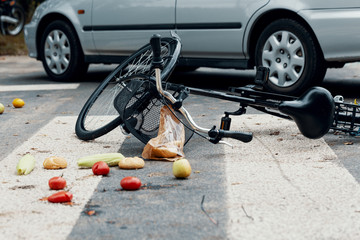 Fruits and broken bike on pedestrian crossing after collision with a car