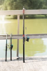 Fishing rod, spinning reel on the background pier river bank. Sunrise. The concept of rural getaway. Article about fishing day.