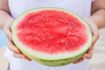 Young Woman Holds in Hands Juicy Ripe Halved Watermelon by Swimming Pool . Sunlight. Vacation Relaxation Summer Vibes. Authentic Atmosphere. Lifestyle. Poster with Copy Space
