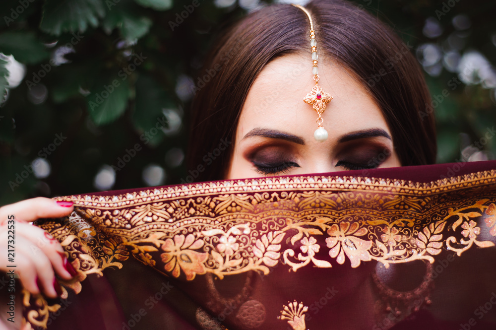 Wall mural portrait of beauty indian model with bright make-up who hiding her face behind the veil. young hindu