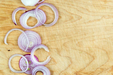 Sliced red onion rings on wooden background top view with space wor text