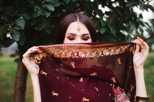 Portrait Of Beauty Indian Model With Bright Make-up Who Hiding Her Face Behind The Veil. Young Hindu Woman With Mehndi Tattoos From Black Henna On Her Hands.