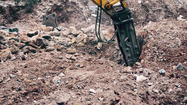 Close up of a heavy duty construction industry excavator machine crushing stones in a construction site