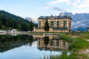 Fototapeta premium Buildings along the shoreline are reflected in the calm waters of Lake Misurina in the Italian Dolomites, just before sunset.